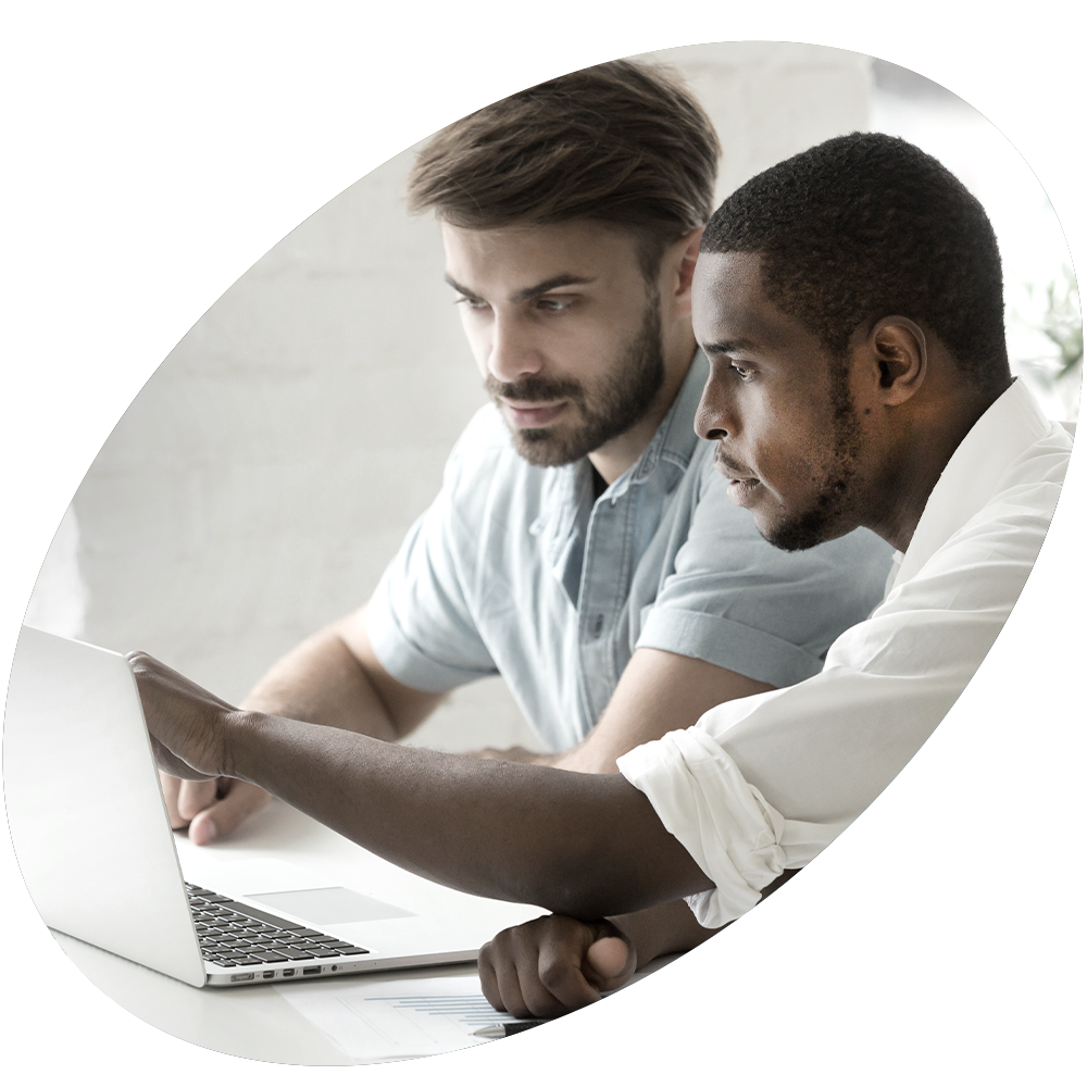 Two men look at laptop.