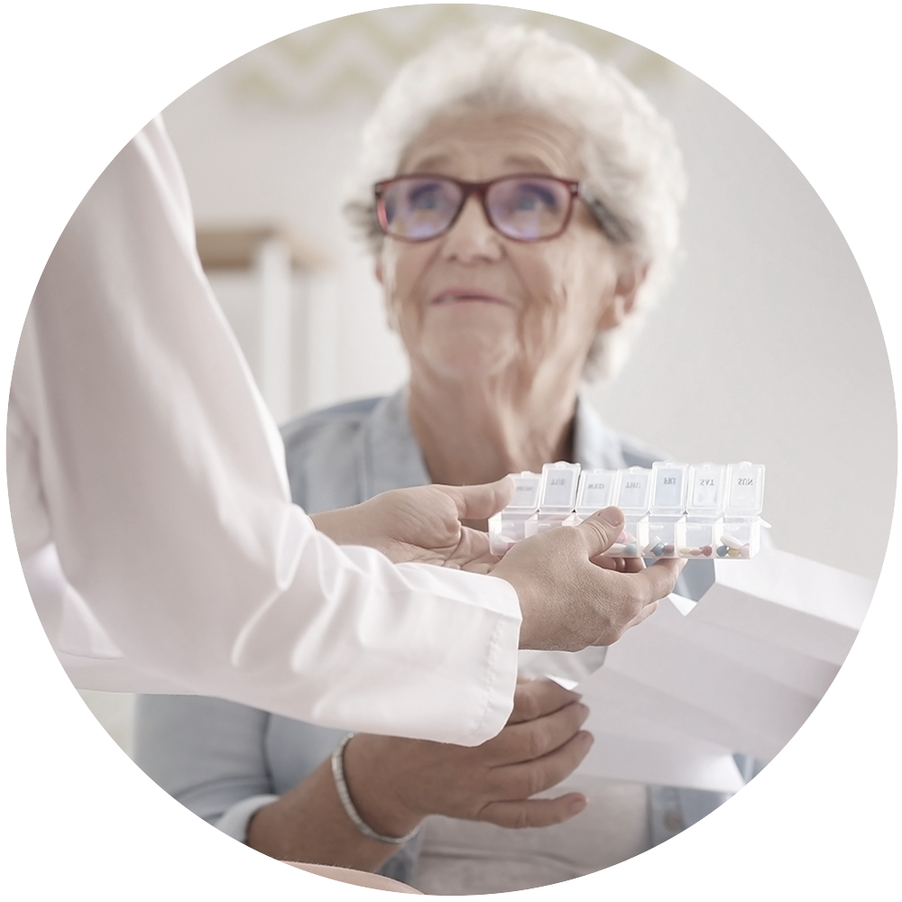 elderly woman holds paper while looking at a provider who is holding a pill box.