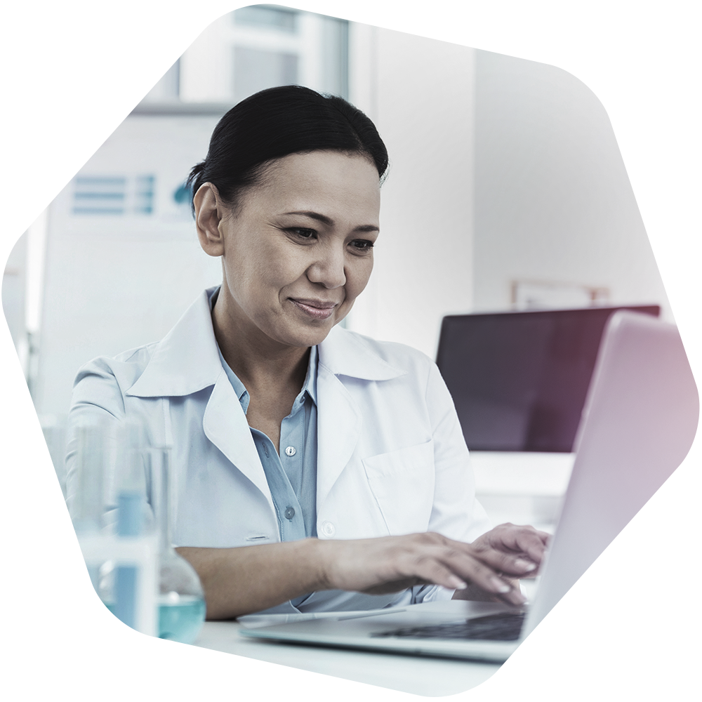 Woman in whitecoat working on laptop.