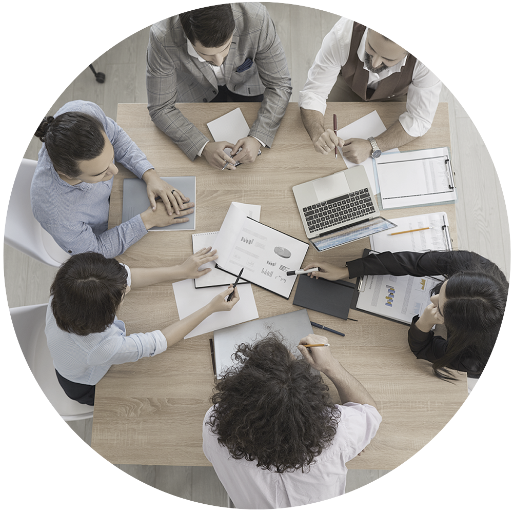 Overhead shot of six individuals working together at a desk.