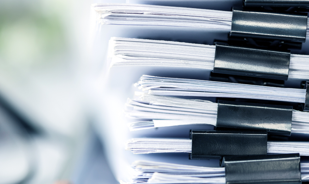 stack of paperwork with reading glasses