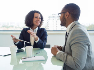 Joyful business woman holding tablet and talking to male colleague in a meeting.