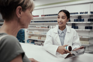Female pharmacist guiding customer with prescription on digital tablet