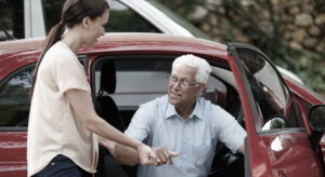 Woman helping older male out of the car.